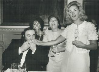 Lending a hand, Operatic superstar Luciano Pavarotti bestows a joint kiss of appreciation on hostess Sally Stavro, centre, and Claris Fulci, right, wi(...)
