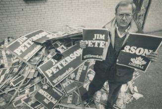 Bitter race, Liberal Jim Peterson, a candidate in Willowdale, stands amid a mountain of vandalized signs