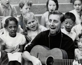 They sing for our land. Folk singer Klaas Vangraft leads a group of children representing nine nationalities in the singning of This Land is My Land d(...)
