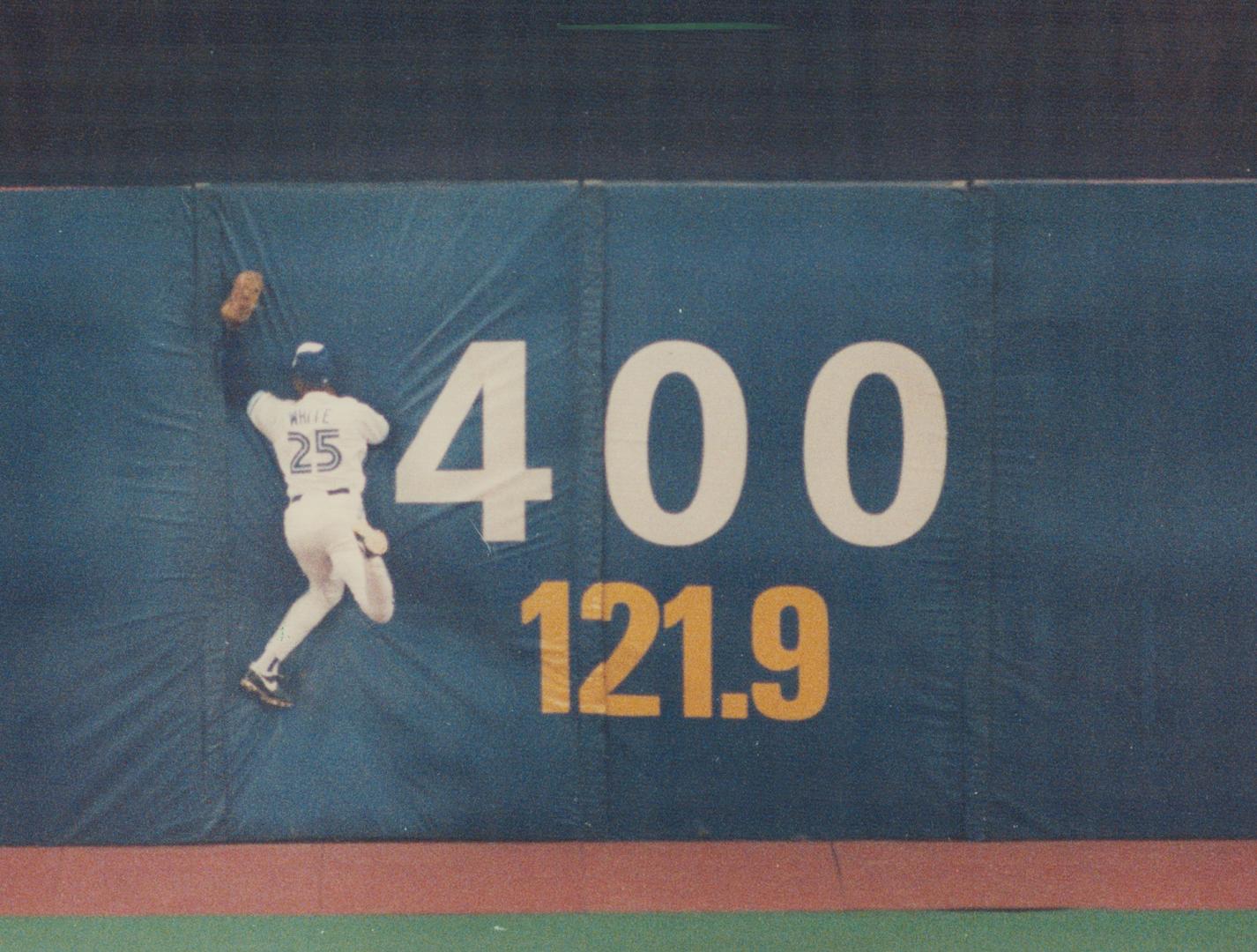 Toronto Blue Jays player jumping to catch ball into barrier with the numbers 400 and 121 point  ...