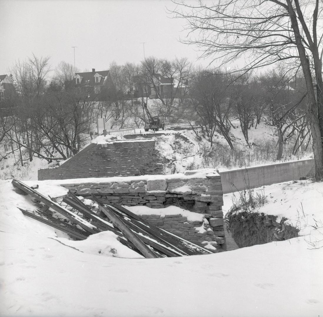 Old Dundas St., looking west across Humber River, showing truck drawing up sections of bridge after it was toppled into the river. Toronto, Ontario