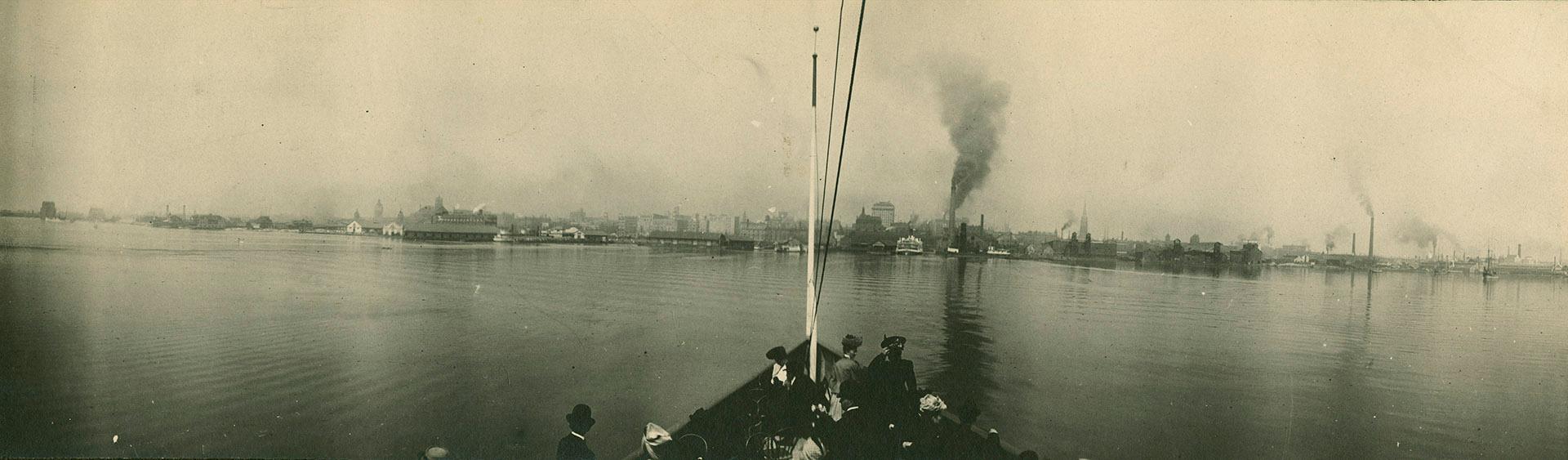 Image shows a number of people on the boat with the Harbour in the far background.