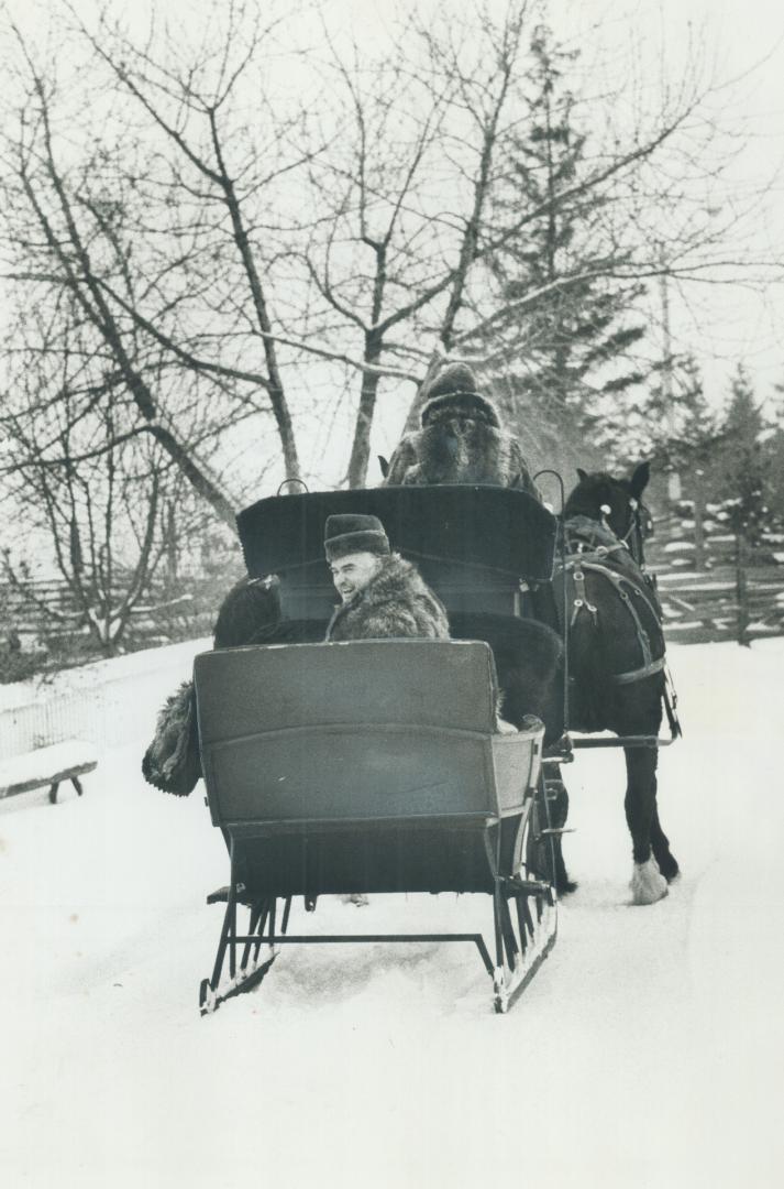 Premier John Robarts, in coonskin coat, rides in a horse-drawn cutter yesterday at Black Creek Pioneer Village during filming of his final Christmas m(...)