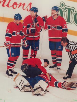 Down and out: Patrick Roy receives attention from the Montreal trainer after a second-period collision with Wendel Clark, Roy was forced to leave the game