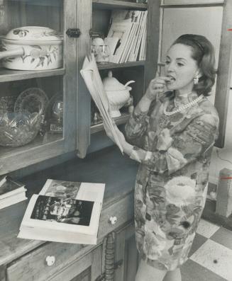 Mrs. Jan Rubes checks recipe in her only set of cookbooks. When she entertains she usually relies on menu from her own recipe collection