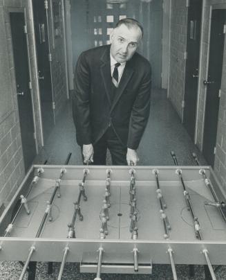 Superintendent Walter Rutledge plays with a toy soccer game in cell area of improved York County detention home for children on Jarvis St. Critics use(...)