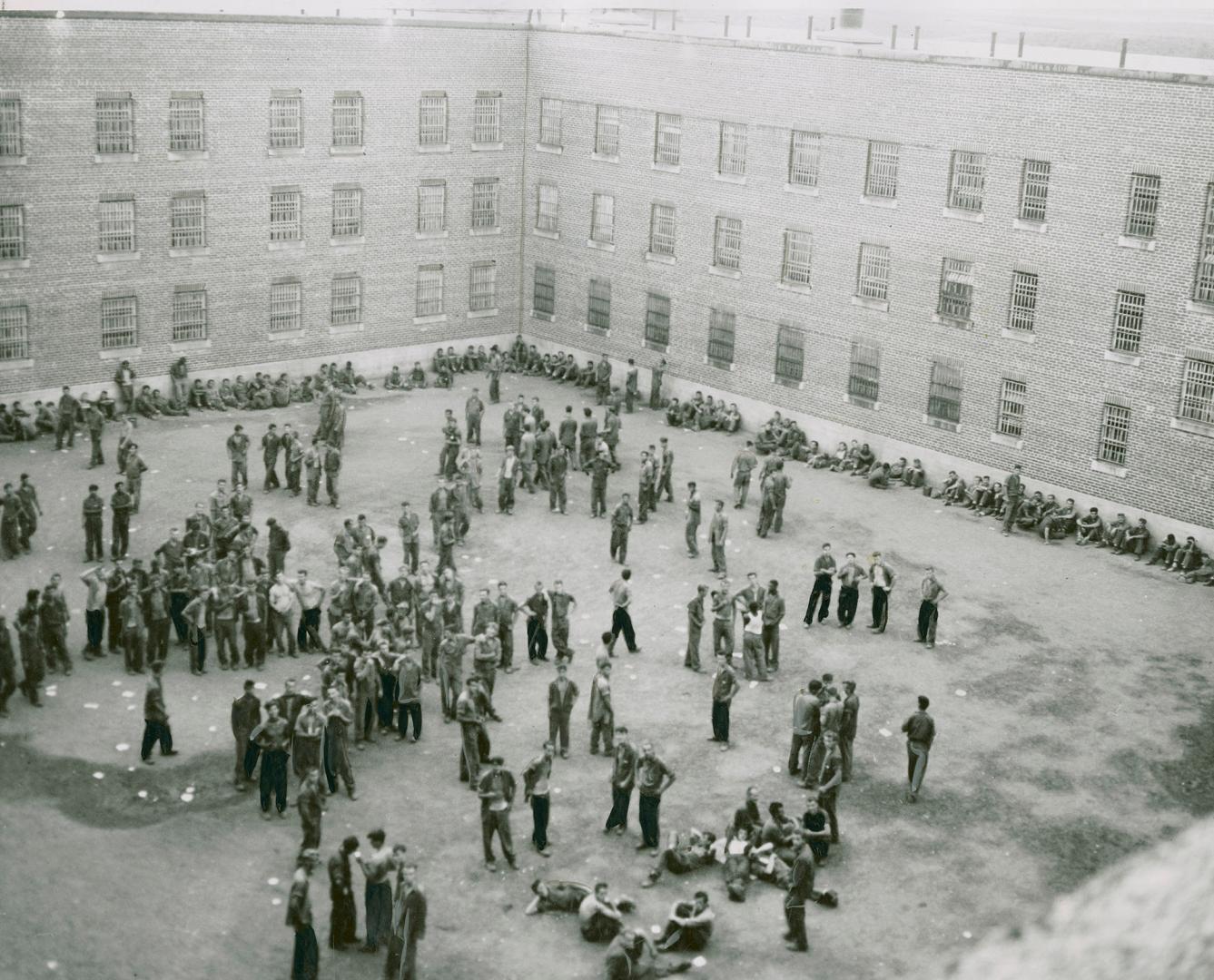 Quelled convicts are shown above standing in courtyard of Guelph Reformatory today after three outbreaks of rioting in three days
