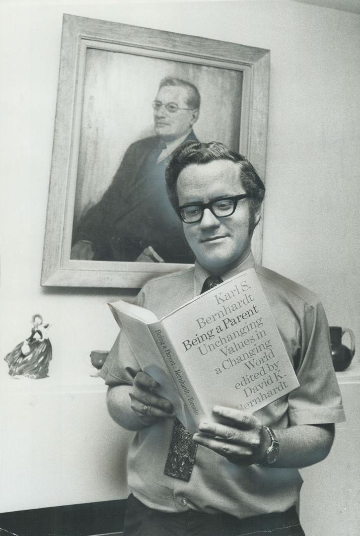 Prof. David K. Bernhardt holds a book, Being a Parent, he co-authored