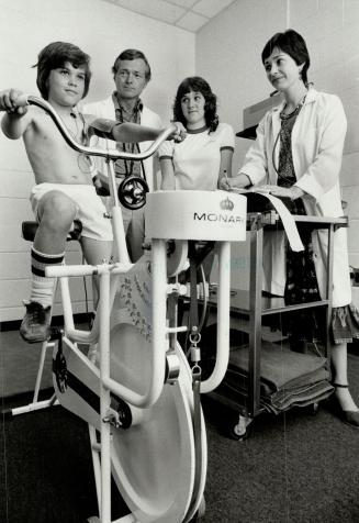 Finding out: Ten-year-old David Laverty peddles a bicycle at The Fitness Institute to test his cardiorespiratory efficiency level as his sister Jenny, medical director Dr. Frank Berka and Tanja Parsley, testing and fitness director, offer moral support.