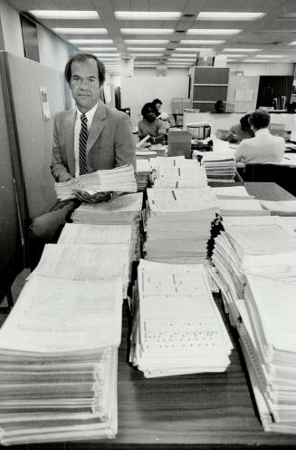 Paper flood: Director orf Ontario's student awards program, Bill Clarkson, above, sifts through a mountain of applications from students seeking financial assistance with their post-secondary education. Philip Lam talks with personal loans manager Murray Dowey, right, at the Bank of Montreal.