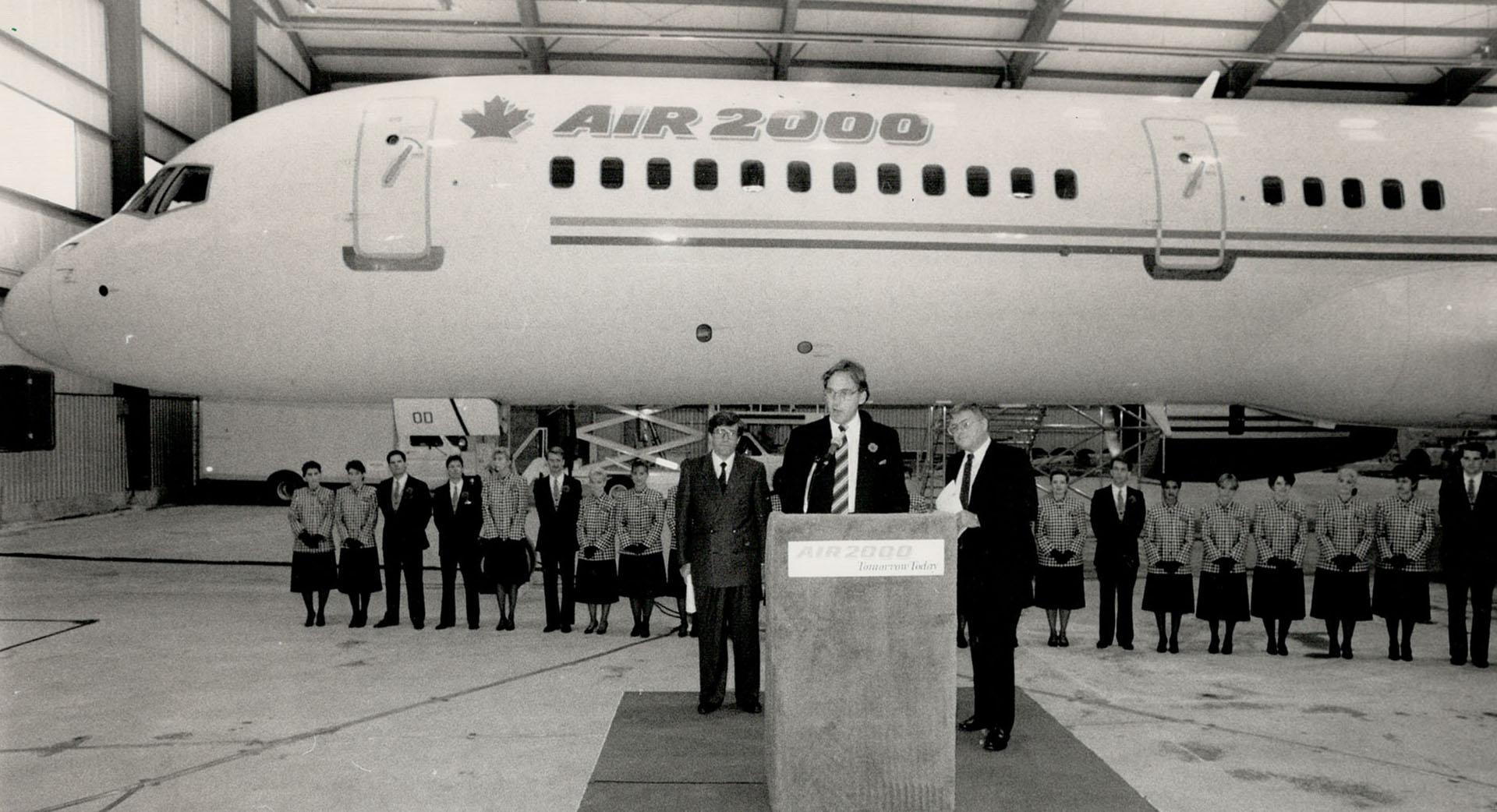 Ready for takeoff: With a Boeing 757 in the background, John Lecky, chairman of Air 2000 Canada, tells employees that the Deluce family has brought a 25 percent interest. With him are Robert Deluce, left, and Paul Jervis.