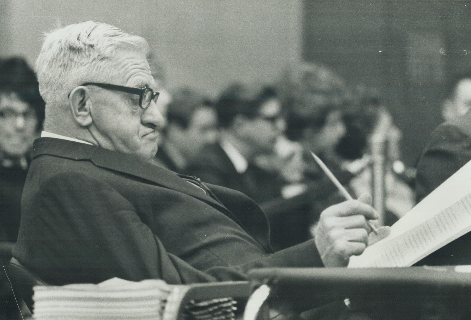 Man with white hair leaning back and reading some papers is J. Gordon Gibson