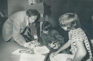 Meeting the people when he ran for the Legislature last fall as the Liberal candidates in Scarborough West, Norman Kert signs pictures for two young admireers at an all-candidates' meeting