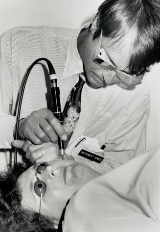 Light therapy: Dr. Robert Jones of Oakville uses a special laser to remove a mark from a patient's face.