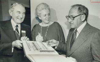 Jack Levine tries out golden pencil. Looking on are Paul Higgins, left, and Mrs. Jean Pigott