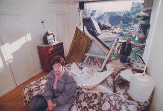 Nurse Cathie McBride sists in shocked disbelief today in what remains of her Etobicoke bedroom while her husband, Gene, looks in from the outside