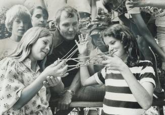Stringing a figure: Professor Ken McCuaig (middle) and other members of the Applewood String Band watch as his daughters, Peggy (left), 11, and Lisa, 13, create a complicated figure using two string loops together