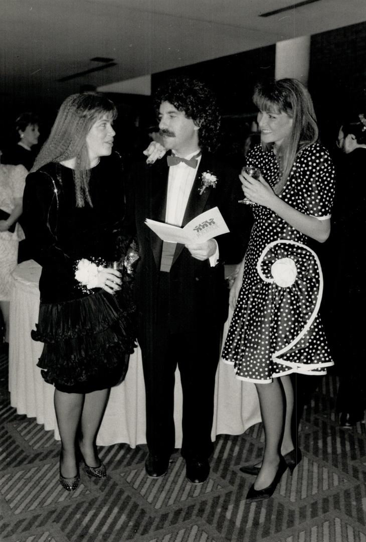 Freelance writer Judy Nyman, left, looks over the program with her husband, chartered accountant Harley Mintz, chairman of the board of the Reena Foundation, as Lisa Raphael looks on
