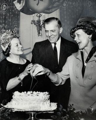 U.S. consul cuts up - a cake. Allen B. Moreland, new United States consul in Toronto, found one of his first duties a pleasant one, cutting the cake at the 49th birthday party of the American Women's Club of Toronto. Mrs. W. F. Bebell, left, president of the club, and Mrs. Moreland, right, gave the consul some help. Party was in ballroom of King Edward.