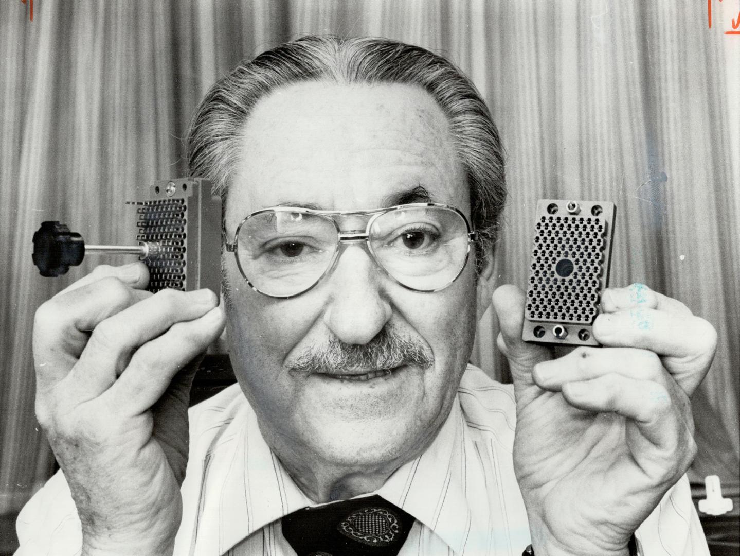 Milton Stark holds a connector for a computer terminal, one of his firm's products