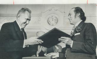 Canada's copy of an agreement under which the Soviet Union and Canada will exchange scientists, academics, students, artists and sportsmen is handed to Prime Minister Pierre Trudeau by Soviet Premier Alexei Kosygin after the pact was signed in Ottawa yesterday
