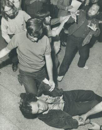 Stunned and bleeding, Edmund Burke Society spokeman Paul Fromm, 21, is aided by an associate after being knocked to the floor last Monday