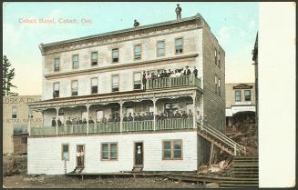 Colorized photograph of a four story hotel building with crowds standing on it's front porches.