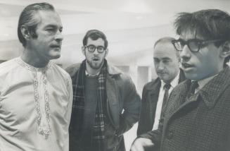 Timothy Leary, high priest of LSD, in long white robes with gold braid down the front, confers with Allen Kamin, University of Toronto sociology student (right) on ways of getting tape-recorded sermon into Canada