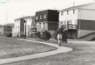 Woman and stroller walking a path along the back of houses. Ajax, Ontario
