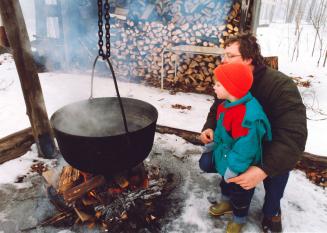 Terry Wiegard and his son Brian watch maple sap being heated in a cauldron. Bruce's Mill Conservation Area, Ontario