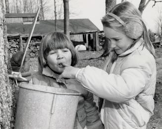 Kimberley and Kristy Kennedy sample maple sap at Bruce's Mill Conservation Area, Ontario