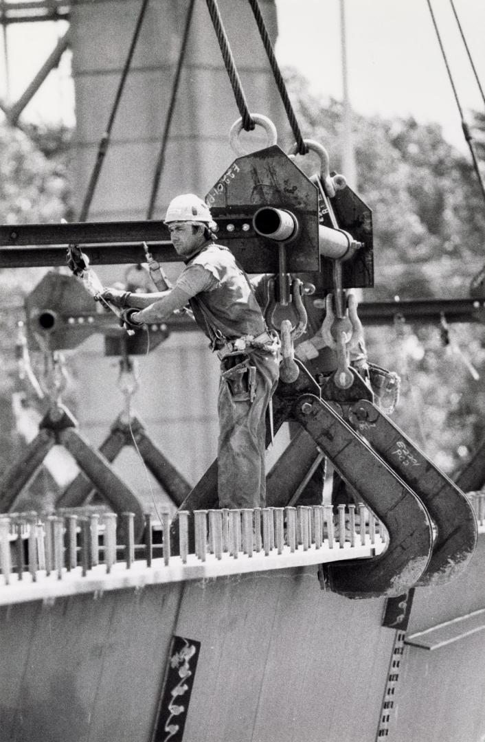 Steelworker joining 100-tonne beams to the concrete supports of the new Burlington Skyway span. Burlington, Ontario