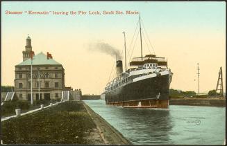 A large metal steamer in a lock, passing a 4-storey stone building.