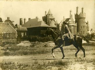 Image shows a person riding a horse outside Casa Loma.