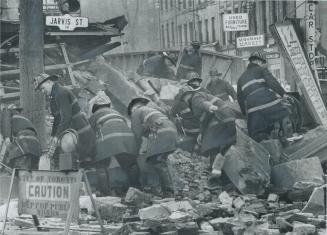 Searching for bodies, city firemen comb through the rubble of the east wing of St