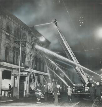 Firemen pour water on burning star annex on king St