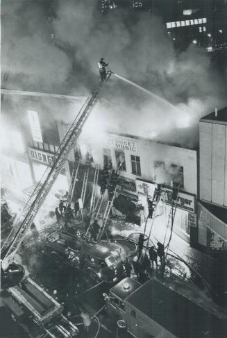 Firemen pour water into blazing stores on Yonge St