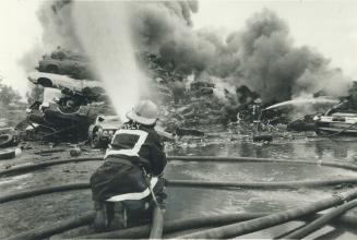 Wrecking yard catches fire. Firemen turn their nozzles on a 30-metre (100-foot) pile of tires that caught fire yesterday and sent up a large plume of (...)