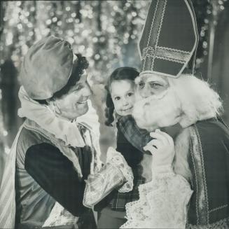 St. Nicholas comes to town. One of his six Moorish servants, called Piets or Peters, and played by Jan Spekkers, holds up Audrey de Man, 4, as she hug(...)