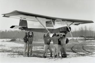 Workers at Baldwin Airport, north of Newmarket, hoist a Macair Merlin ultralight plane on their shoulders to carry it to a trailer for transport to th(...)