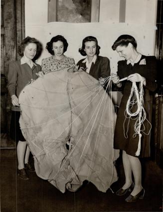 Employees of the Ontario department of lands and forests look over a new-type parachute being used to drop emergency supplies to persons stranded in i(...)