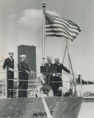 Showing the flag. Crewmen of the USS Havre-in Toronto on a centennial year goodwill tour until saturday-are outlined against the city's rapidly burgoening and changing skyline