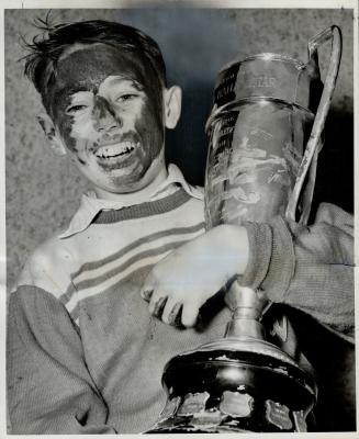 Frank La Feuvre, captain of Withrow bantams, hugs The Star trophy which his team won with a muddy 1-0 victory over Davenport in yesterday's intermedia(...)