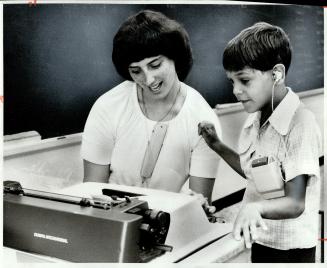 Teacher Gayle Haley shows 9-year-old Chris Butler how to operate electric typewriter as one method of communication for deaf or partially deaf childre(...)