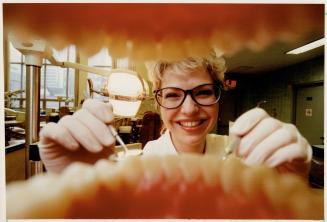 Getting inside a smile. While Maria Tarka, a 4th year dentistry student at the University of Toronto, practises on a dummy's bicuspids, dentists and d(...)