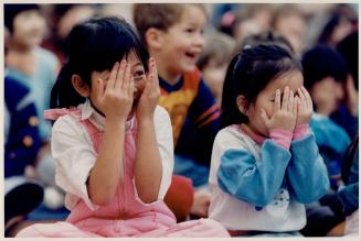 Hiding behind happy hands, George Syne Public School students Chhorvy Prak, 5, left, and Lena Lam, also 5, play peek-a-boo with puppets at a puppets a(...)