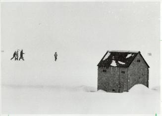 Armed with rods and saws, a group of hopeful fishermen, just specks in distance, head to an ice hut to begin the day's sport