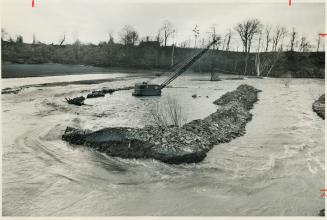 As the Credit River, swollen by spring runoff and heavy rain, rose alarmingly workmen abandoned a construction site south of Streetsville, building a (...)