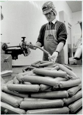 Thousands of dogs, Leszek Chmielowski packs hot dogs in casings at J