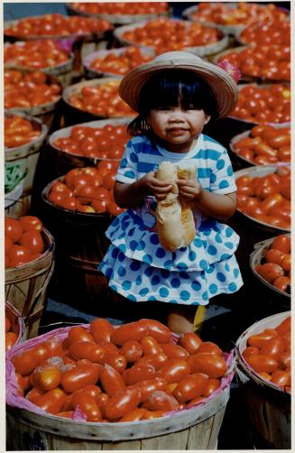 Monique enjoys the market, Monique Chiam, 2, munched a hot dog and checked out the tomatoes when she and her mother Ping visited the Farmers Market at Square One in Mississauga recently